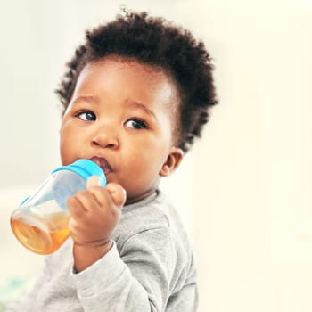 Shot of a little baby boy drinking froma sippy cup at home.