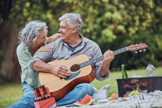 Music, guitar and a senior couple on picnic in park laughing with food, drinks and romance in retirement. Nature, love and elderly man and happy woman on romantic date on the grass on summer weekend