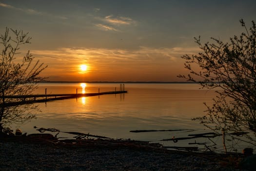 a beautiful sunset over the chiemsee in Bavaria in Germany with a wooden platform in the foreground