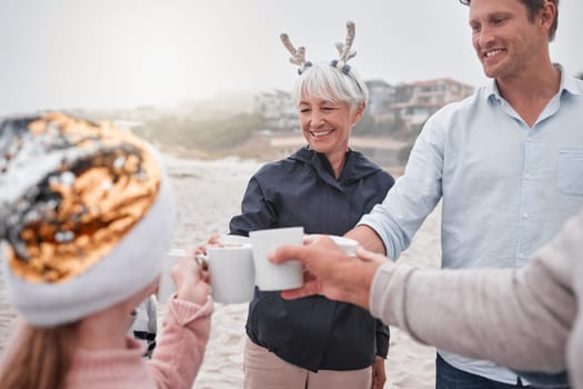 Family, Christmas and holiday celebration on beach with drinks, smile and cheers. Happy man, senior woman and child celebrate spending time together on December ocean vacation drinking hot chocolate
