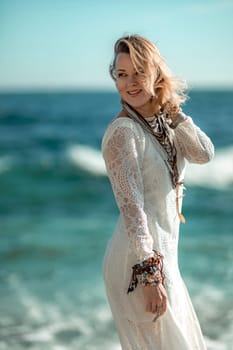 Woman beach sea white dress. The middle-aged looks good with blonde hair, boho style in a white long dress with beach decorations on the neck and arms