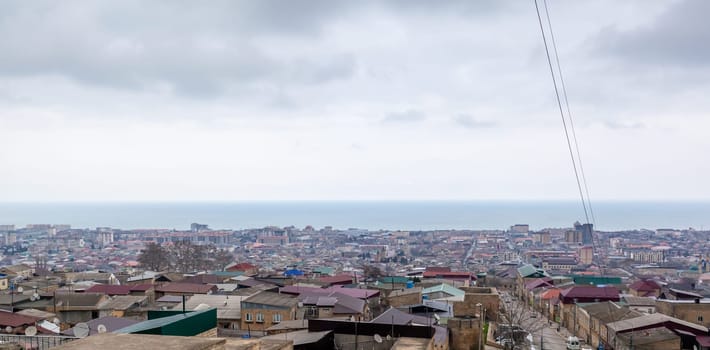 Old town along the blue sea, top view. The ancient city of Derbent in Dagestan with streets and houses is located next to the fortress.