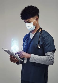 Man, doctor and digital tablet for global communication or healthcare research with covid mask. Male medical expert on technology for data, networking or hologram against a grey studio background.