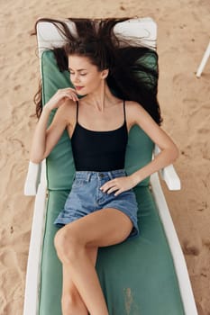 woman lying brunette bikini resort hat tan beach young sea sitting ocean blue recreation relax swimwear smiling sunbed female lifestyle sand