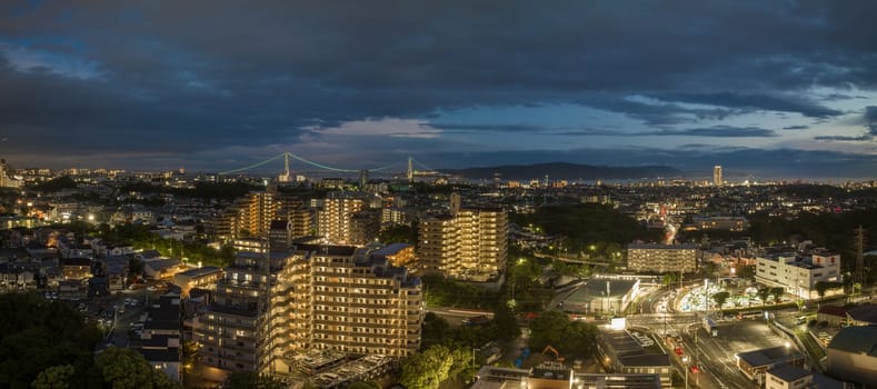 Lights from apartments and intersection in city with distant bridge at night. High quality photo