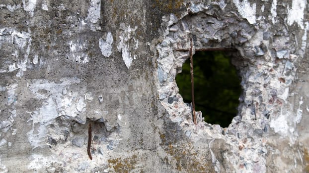 Photo of a broken cement wall or fence. Stone grunge odd wall with a hole. Damaged grungy crack and broken concrete wall