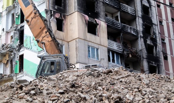 Excavator with hydraulic crusher at the demolition of a residential building. City renewal. Dismantling, destruction of a high-rise multi-storey building for reconstruction. Debris clearing