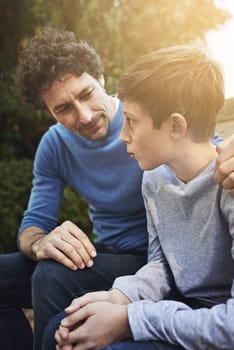 Family, father and son have conversation in backyard, bonding with love and care, communication and relationship. Man help by giving teen boy advice at home, outdoor together with trust and support.