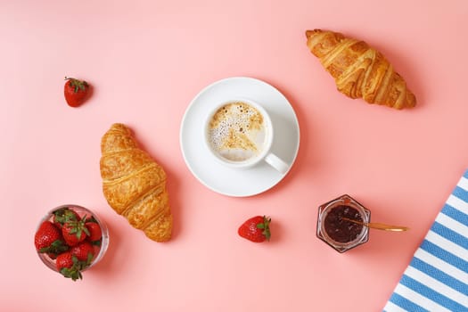 Delicious breakfast with fresh croissants, coffee, berry jam and fresh berries on a pink background.