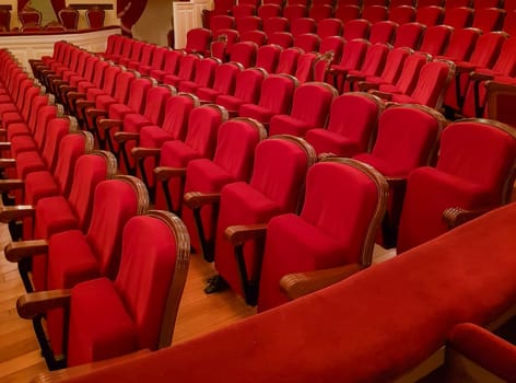 Close-up of traditional, classic empty chairs upholstered in red velvet, the interior of the theater.