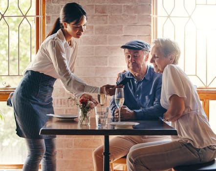 Phone, payment and restaurant with a senior man and woman payng a bill payment with NFC technology a waitress. Dating, romance and retirement with an elderly male and female pensioner in a cafe.