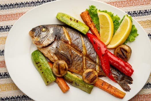 Whole fried fish in a white plate with lemon and vegetables