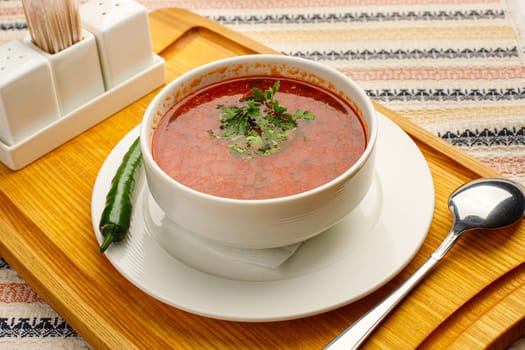 Beetroot soup borsch with garlic, chilly pepper and dill in a white bowl