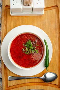 Beetroot soup borsch with garlic, chilly pepper and dill in a white bowl