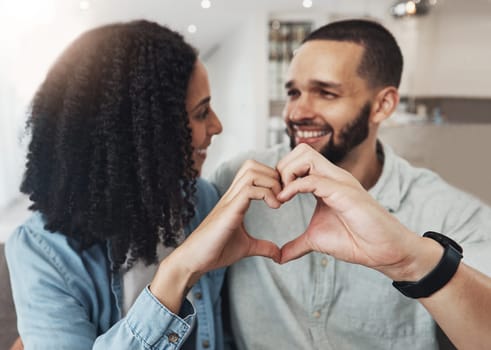 Love, heart hand sign and happy couple enjoy quality time together, bonding and relax on home living room sofa. Eye contact, emoji gesture and marriage people, man or woman smile in good health.