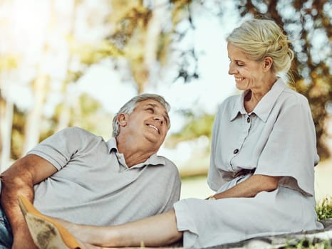 Retirement, love and picnic with a mature couple outdoor in nature to relax on a green field of grass together. Happy, smile and date with a senior man and woman bonding outside for romance.