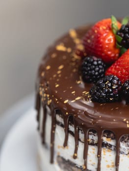 pastry chef preparing a chocolate frosted dripped icing cup cake with sweet fruit topping and golden brush strokes