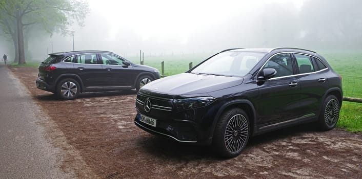 Uelsen, Germany - May 15 2023 Two similar cars parked beside each other on a foggy day. Both are black all electric Mercedes Benz EQA 250