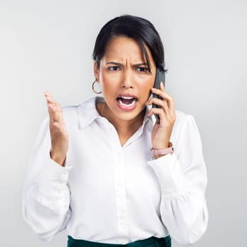 I said sell when it goes up. Studio shot of a young businesswoman using a smartphone and yelling against a grey background