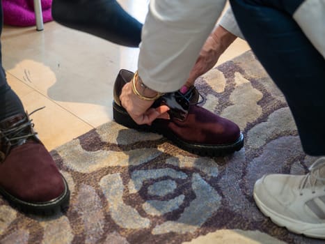 unrecognizable woman in the shop trying new shoes. Caucasian woman sitting in a shoe store while chooses new pair of italian sneakers.