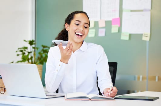 Are we still on for our meeting. an attractive young businesswoman sitting alone in the office and using her cellphone while writing notes