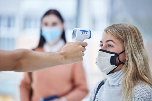 Covid, travel and safety thermometer security test at airport for healthcare protocol inspection. Travelling woman with face mask for coronavirus fever check with medical screening worker