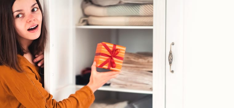 A funny young girl is in a hurry to hide a gift for a loved one, husband, children, friends and parents, a woman wants to make a surprise and hides the gift in the closet during holidays.