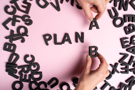 Top view of the scattered letters and the inscription, folded into the words plan a, the hands of people replace the letter a with b. Creative concept about plan b, strategies and opportunities.