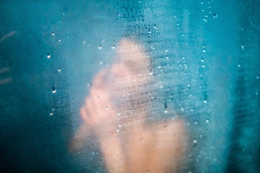 A young smiling girl takes a shower, washes with shampoo in a modern shower cabin, a woman relaxes, taking bath procedures, takes care of the beauty and health of her body.