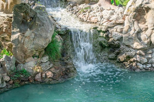 beautiful artificial cascading waterfall with turquoise water close-up