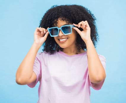 Black woman, sunglasses and smile on a blue background with happy positive attitude and casual summer style. Portrait of African American female, person or lady model smiling in happiness for fashion.