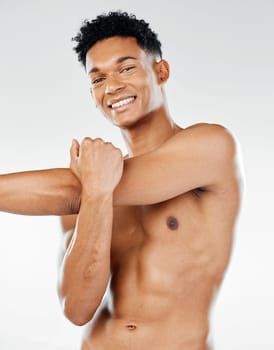 Portrait, fitness and man in studio stretching his shoulder and arms for a body exercise, training and workout. Smile, healthy and happy fitness model getting ready to start exercising with a warm up.
