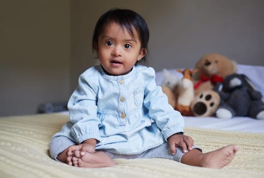 Baby, cute and innocent with a girl on a bed in her home alone with a teddy bear and stuffed toys in the background. Children, small and pure with a female kid in her bedroom in a house in India.
