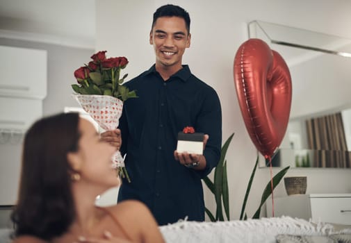 Surprise, love and man with a gift and roses for his wife for valentines day, romance or anniversary. Happy, romantic and husband with present and bouquet of flowers for his woman in the living room