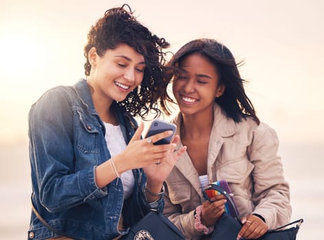 Friends, phone and happy on social media outdoor for interracial creative content, streaming video online or web communication message app. Women, diversity and friendship or reading on smartphone.