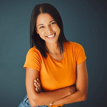 Portrait, fashion and arms crossed with a woman in studio on a gray background for confidence or positive attitude. Happy, smile and confident with an attractive young female posing indoor for style.