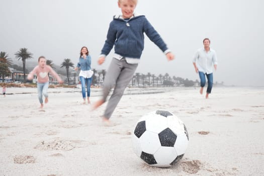 Family, soccer and beach playing on sand together for fun bonding time for sports and exercise in nature. Happy children and parents in playful fitness for football game on a sandy ocean shore.