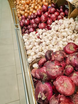 Close-up view of the counter in the vegetable market, sale of onions and garlic of different varieties.