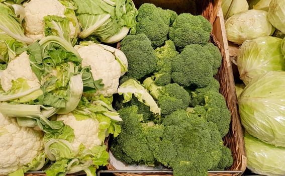 Close-up of a showcase with fresh white cabbage, cauliflower, broccoli in wicker baskets, background of vegetables on the market