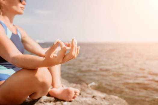 Woman sea yoga. Back view of free calm happy satisfied woman with long hair standing on top rock with yoga position against of sky by the sea. Healthy lifestyle outdoors in nature, fitness concept.