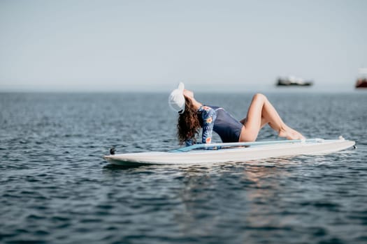 Woman sup yoga. Middle age sporty woman practising yoga pilates on paddle sup surfboard. Female stretching doing workout on sea water. Modern individual hipster outdoor summer sport activity