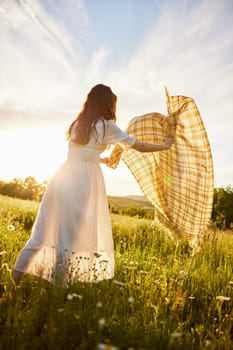 a woman in a light dress in nature spreads a plaid. Sunset, summer. High quality photo