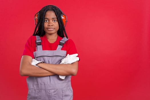 Friendly african woman carpentry worker in work uniform in studio with red background