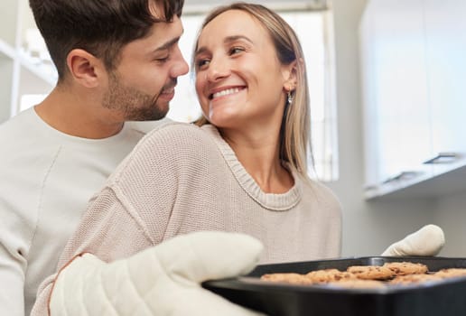Love, kitchen and couple baking cookies together for fun, bonding and romance in their home. Bake smile and happy young man and woman preparing biscuits or snacks for party, event or dessert at house.