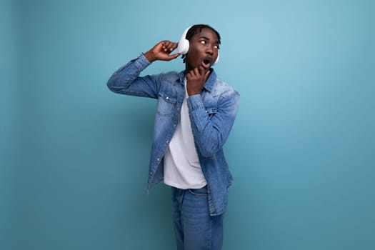 energetic american man with dreadlocks in denim jacket dancing to music with headphones.