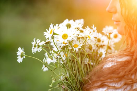 A middle-aged woman holds a large bouquet of daisies in her hands. Wildflowers for congratulations.