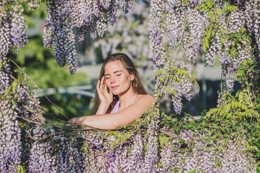 Woman wisteria lilac dress. Thoughtful happy mature woman in purple dress surrounded by chinese wisteria.