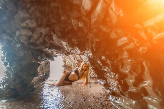 Woman travel sea. Attractive blonde woman in a black swimsuit enjoying the sea air on the seashore around the rocks. Travel and vacation concept