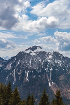 Bavarian Alps. A peaceful winter scene of tranquil snow-covered wilderness with majestic mountains and a dense pine forest.