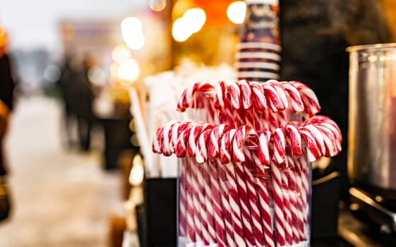 Traditional Christmas lollipop cane candies with red and white stripes at traditional street food festival market. Festive sweets at fair as symbol of Xmas
